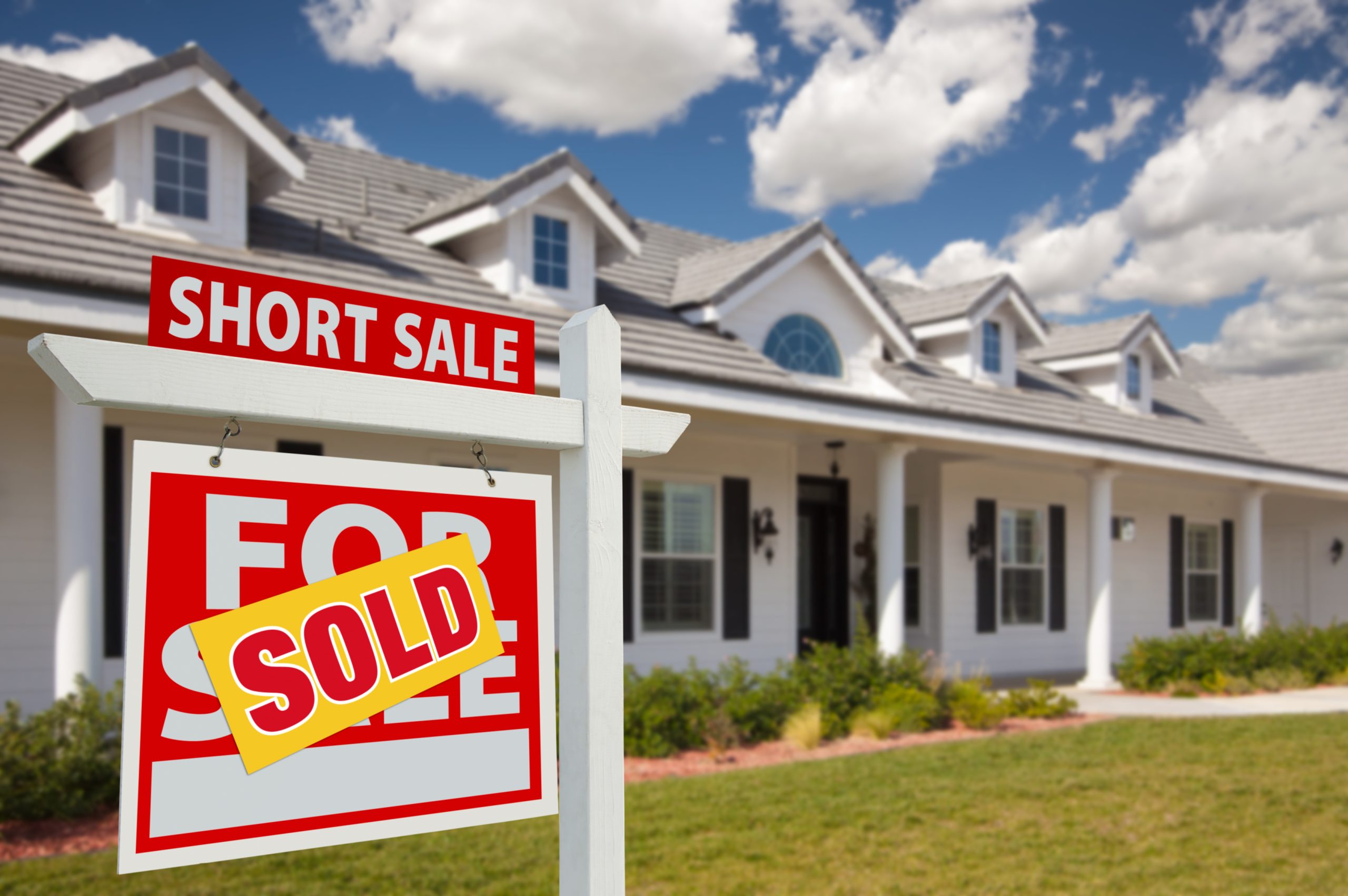 Multi unit building with short sale for sale and sold sign in front.