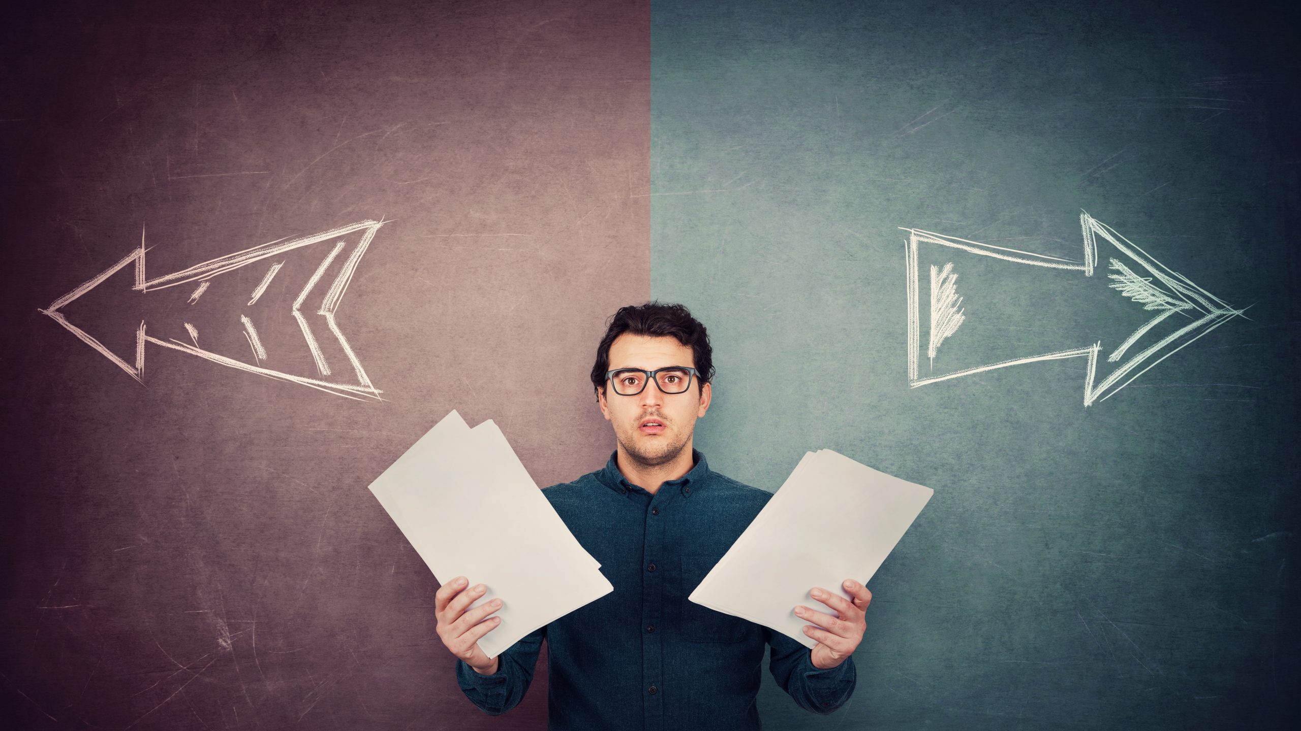 Man in front of wall that shows arrows pointing in two directions like he has to choose