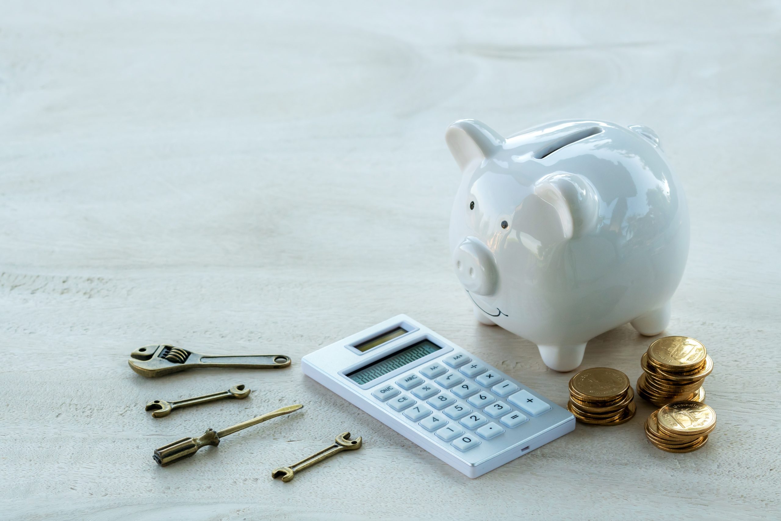 Piggy bank with coins, a calculator, and tools