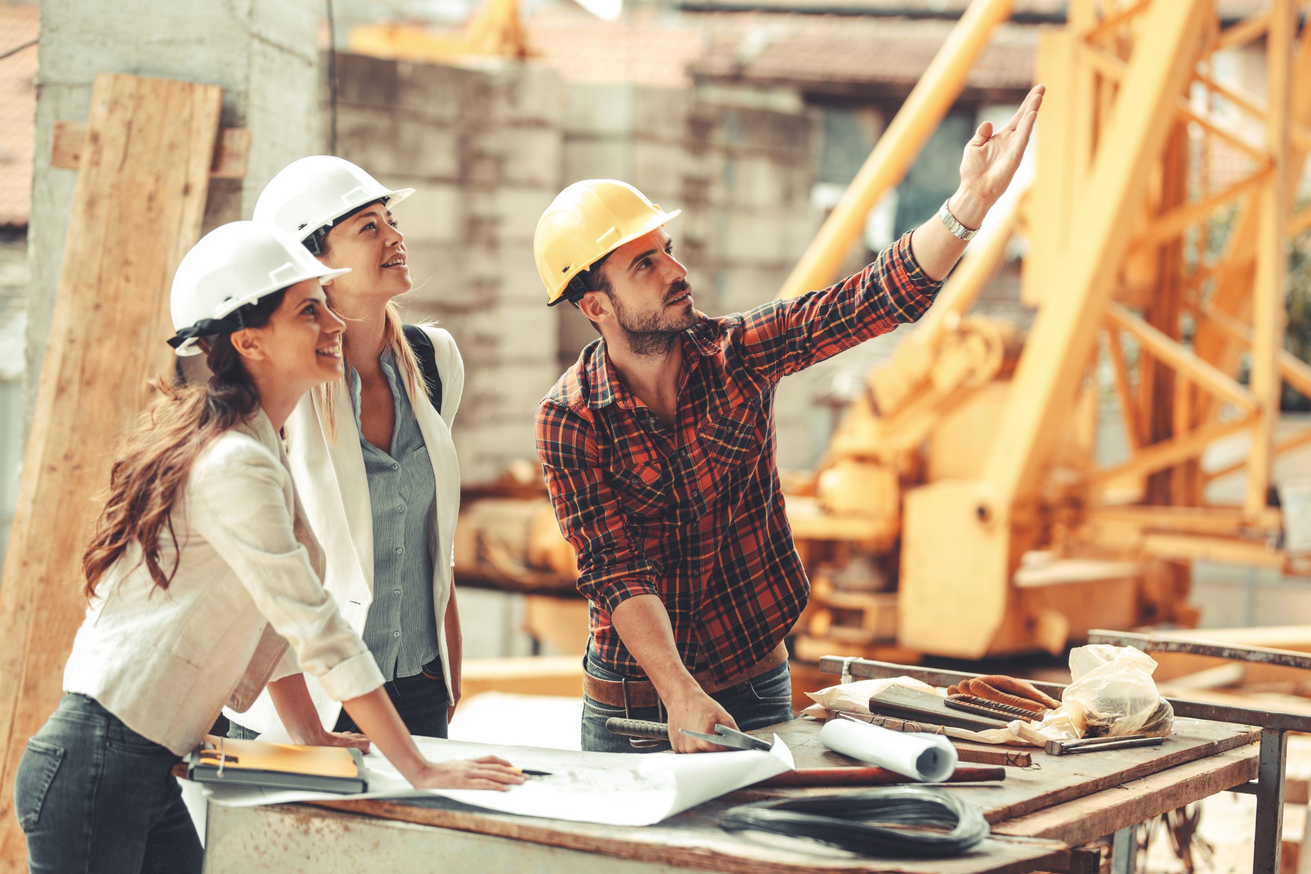 Two female supervisors discuss building under contstruction with laborer